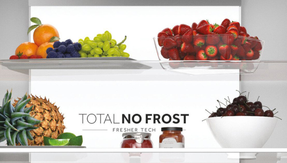 Wnętrze lodówki z owocami na półkach, w tym pomarańcze, winogrona, truskawki, ananas i wiśnie. Widoczny tekst: \'TOTAL NO FROST FRESHER TECH\'.