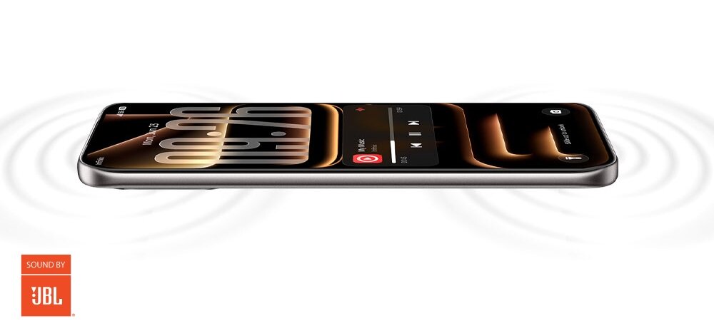 Smartfon leży poziomo, wyświetlając ekran z zegarem i odtwarzaczem muzyki. W lewym dolnym rogu widoczne jest logo \'SOUND BY JBL\'.