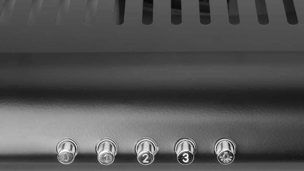 Czarny panel z pięcioma srebrnymi przyciskami oznaczonymi cyframi 0, 1, 2, 3 oraz symbolem wentylatora. Nad przyciskami widoczne są otwory wentylacyjne.