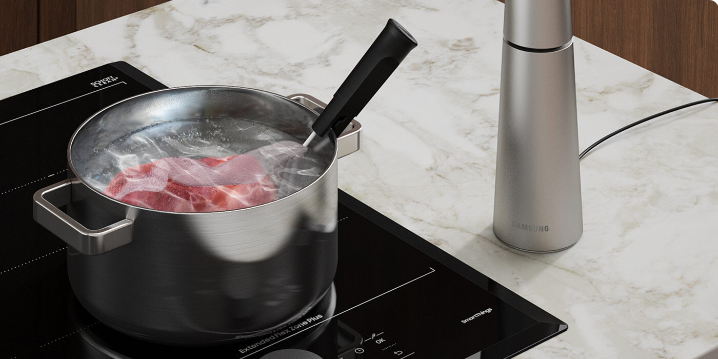 gotowanie z użyciem termosondy - jakie ma zalety dowiedz się na Media Expert Na płycie indukcyjnej znajduje się garnek z gotującą się wodą i zanurzoną w niej termosondą. Obok garnka stoi srebrny pojemnik z napisem \'SAMSUNG\'.