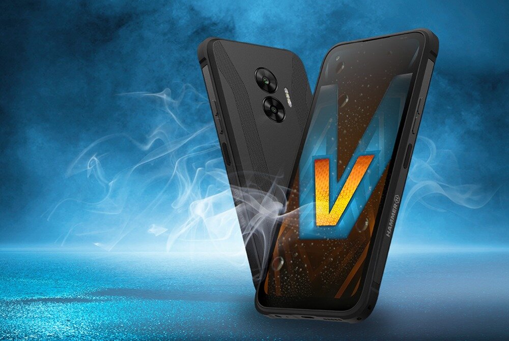 Na obrazie widoczny jest czarny smartfon z dużym ekranem, na którym wyświetlona jest litera \'V\'. W tle widać niebieską poświatę i unoszący się dym.