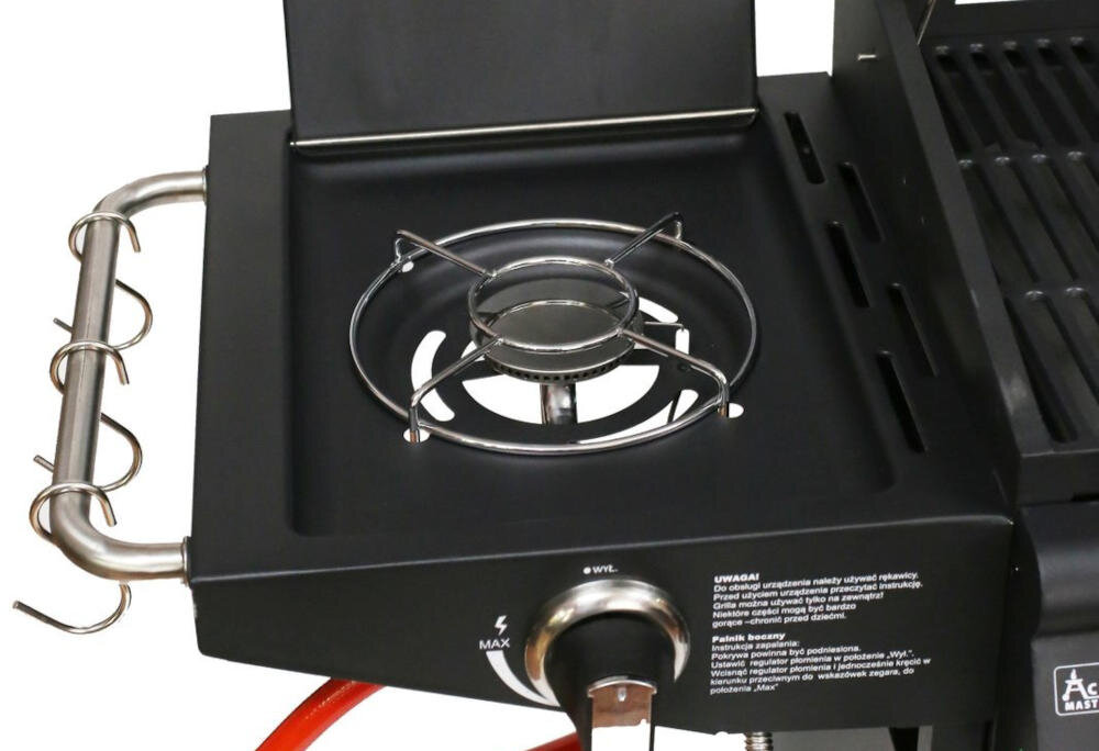 Zdjęcie przedstawia palnik boczny grilla gazowego z metalowym rusztem i pokrętłem regulacji. Widoczny jest również fragment instrukcji bezpieczeństwa oraz logo \'ACTIVA\'.