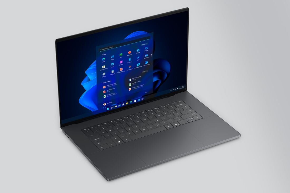 Na obrazie widać otwarty laptop z wyświetlonym na ekranie systemem Windows 11. Klawiatura jest pełnowymiarowa, a obudowa ma ciemny kolor.