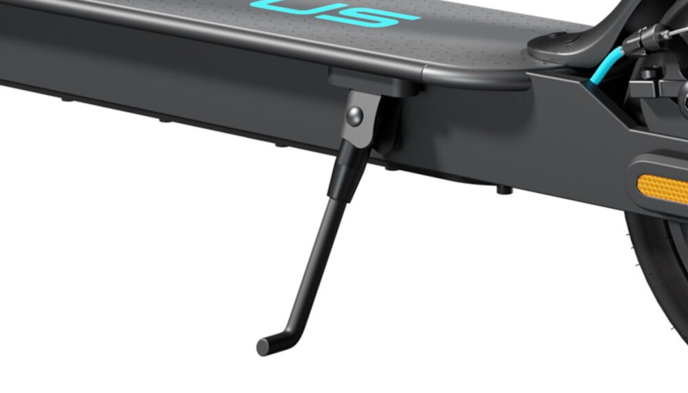 Zbliżenie na dolną część szarej hulajnogi elektrycznej z widoczną podpórką. Na platformie widoczny jest fragment napisu \'US\'.