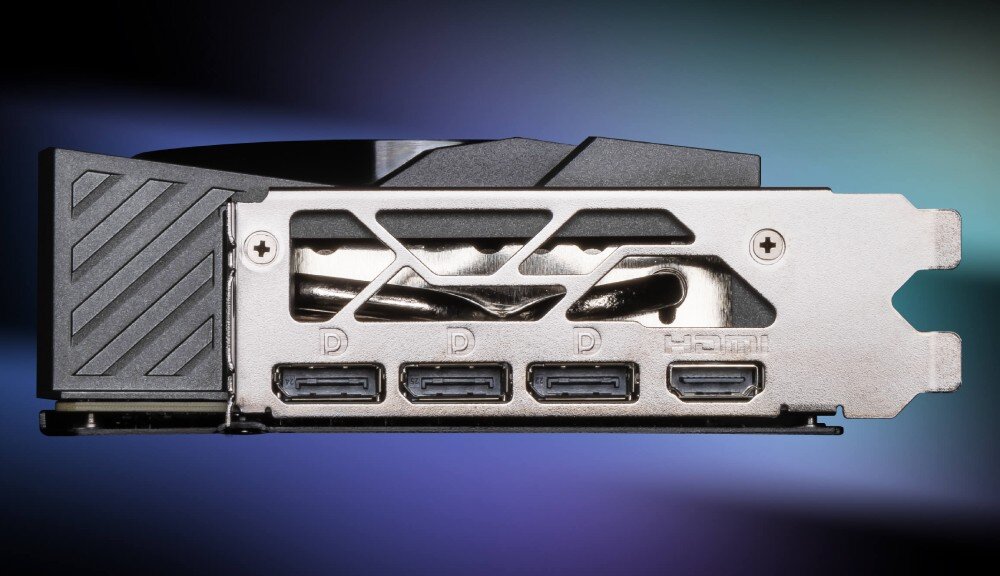 Zdjęcie przedstawia tylny panel karty graficznej z czterema portami, z których trzy są oznaczone literą \'D\', a jeden \'HDMI\'. Panel ma metaliczną obudowę z czarnymi elementami i wzorem w paski.