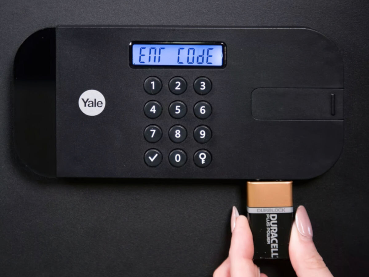 Sejf YALE YSEB 200 EB1, rozpakowanie, podłoga, montaż, ściana, dłoń przykłada baterię do panelu otwierania sejfu