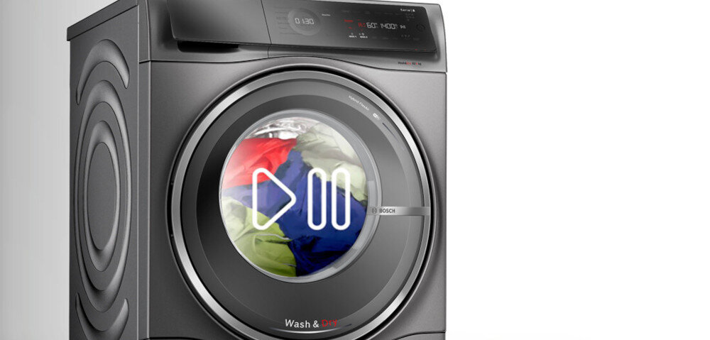 Pralko-suszarka w kolorze szarym z widocznym bębnem, w którym znajdują się kolorowe ubrania. Na drzwiach bębna widoczne są symbole odtwarzania i pauzy oraz logo BOSCH.