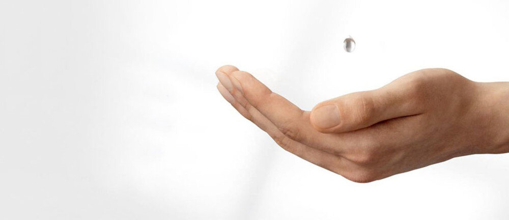 Na obrazie widoczna jest otwarta dłoń skierowana wnętrzem do góry na białym tle. Nad dłonią unosi się mała kropla wody.