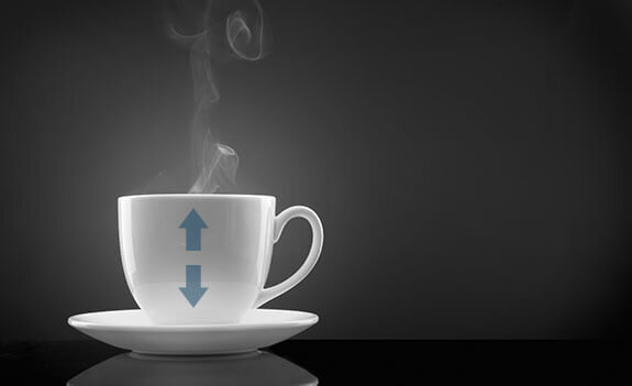 Biała filiżanka na spodku z unoszącą się parą, na której widoczne są niebieskie strzałki skierowane w górę i w dół. Tło jest ciemnoszare.