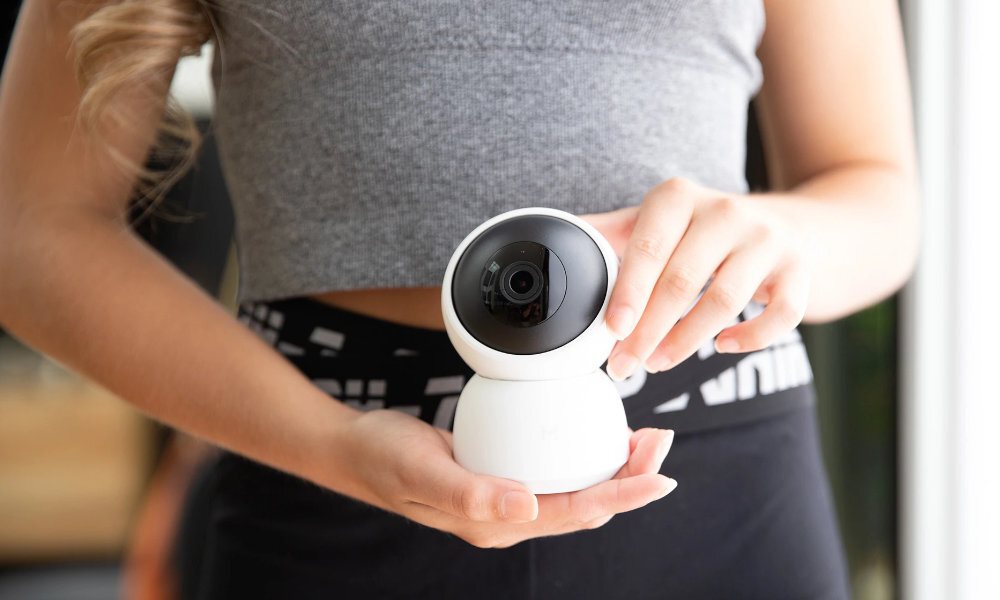 Osoba trzyma białą, obrotową kamerę wewnętrzną z widocznym obiektywem. Kamera ma okrągły kształt i jest trzymana obiema rękami.