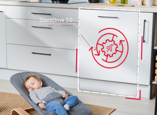 Na obrazie widać kuchnię z białymi szafkami, na jednej z nich znajduje się napis \'SilentDrive 3.0\' oraz czerwony symbol zębatki z dwoma strzałkami. Na podłodze leży śpiące dziecko w foteliku.