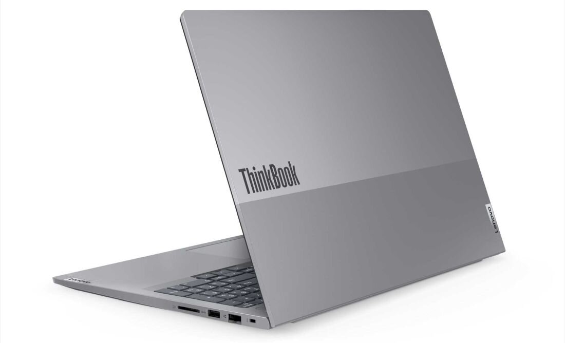 Srebrny laptop z widocznym logo \'ThinkBook\' na pokrywie. Urządzenie jest otwarte, ukazując klawiaturę i kilka portów po boku.
