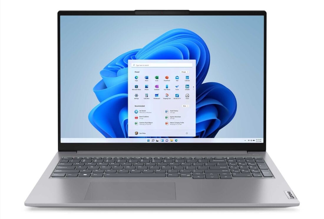 Laptop z otwartym ekranem, na którym widoczny jest pulpit systemu Windows 11 z ikonami aplikacji. Na obudowie znajduje się logo \'Lenovo\'.