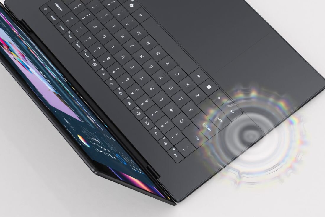 Obraz przedstawia otwarty laptop z widoczną klawiaturą i ekranem. Na powierzchni obok touchpada widoczny jest efekt świetlny przypominający fale dźwiękowe.