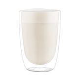 Szklanka z przezroczystego szkła wypełniona napojem o kremowej barwie, przypominającym mleko lub kawę z mlekiem.