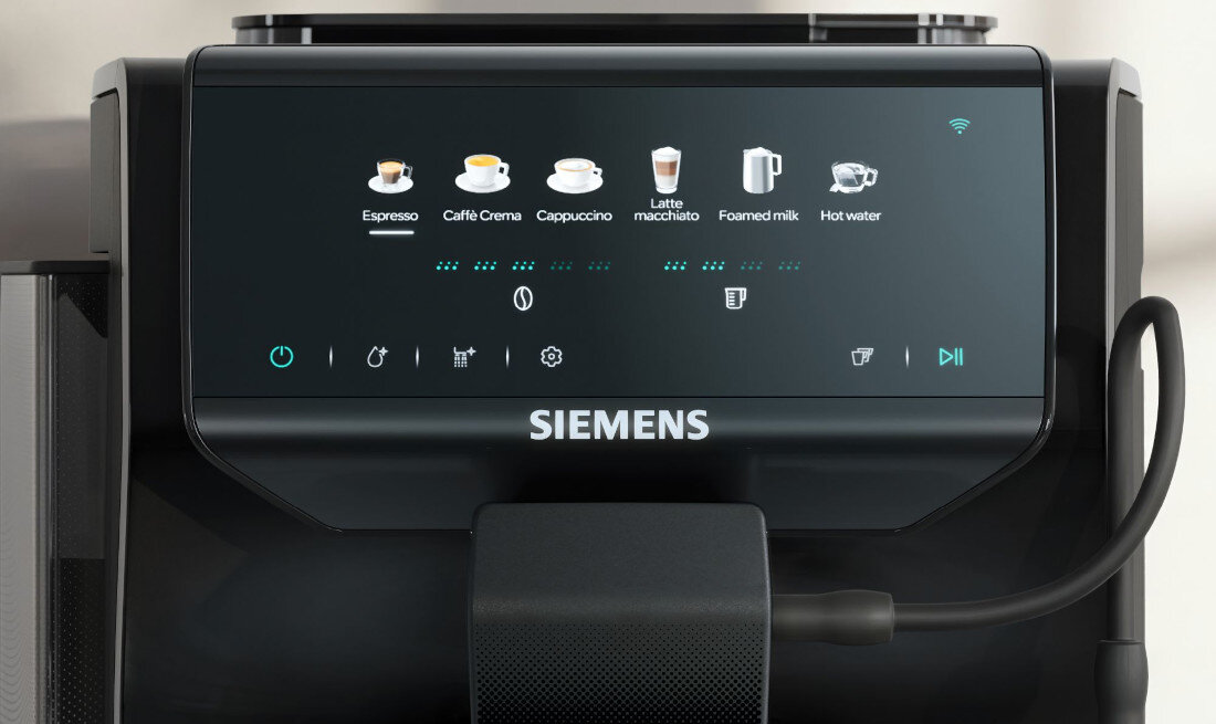 Panel sterowania ekspresu do kawy z wyświetlaczem pokazującym różne opcje napojów, takie jak Espresso, Caffè Crema, Cappuccino, Latte macchiato, Foamed milk i Hot water. Widoczne jest logo \'SIEMENS\' poniżej wyświetlacza.