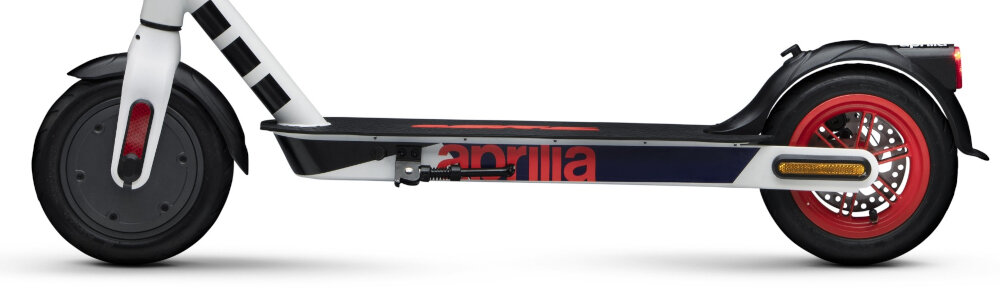 Na obrazie widoczna jest elektryczna hulajnoga w kolorach biało-czarno-czerwonym z napisem \'aprilia\' na boku. Hulajnoga ma czerwone koła i czarną platformę do stania.