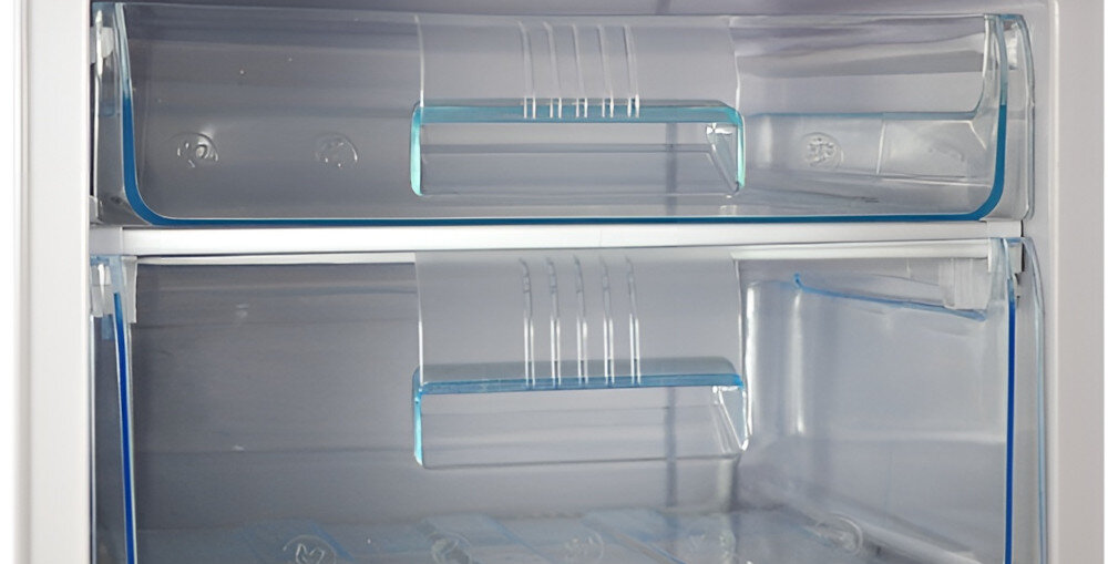 Wnętrze zamrażarki z dwoma przezroczystymi szufladami z niebieskimi uchwytami. Szuflady są puste i wykonane z tworzywa sztucznego.