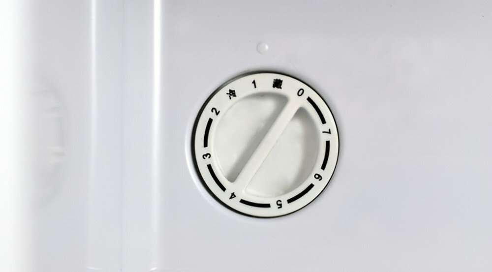 Biały panel z okrągłym pokrętłem oznaczonym cyframi od 0 do 7 oraz symbolami w języku chińskim.