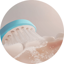 Zbliżenie na główkę szczoteczki sonicznej z niebieskim elementem, która czyści zęby z widocznymi bąbelkami wody.