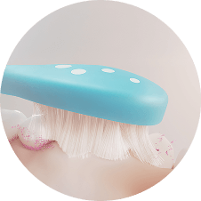 Obraz przedstawia niebieską główkę szczoteczki z białymi kropkami, która szczotkuje zęby z widoczną pianą.