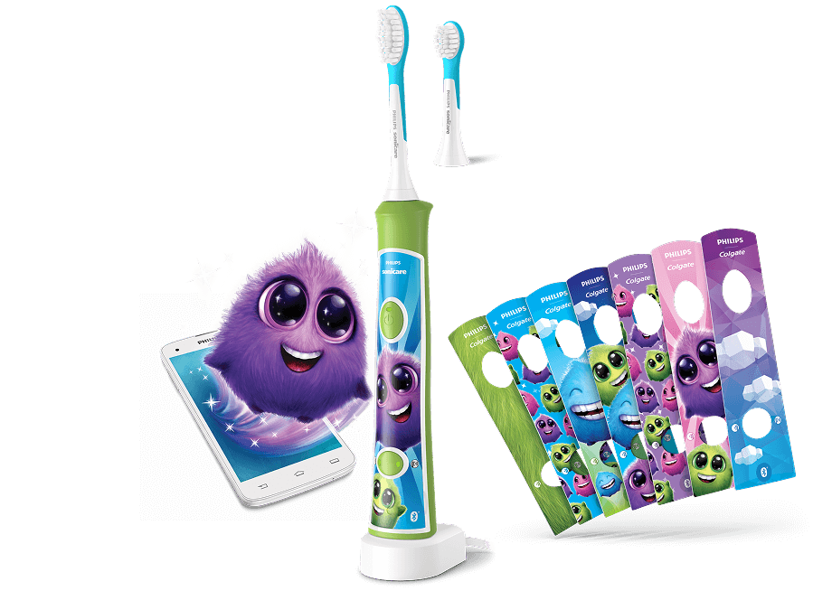 Szczoteczka soniczna z kolorowym uchwytem i wymiennymi końcówkami, obok której znajduje się smartfon z animowaną postacią oraz zestaw kolorowych naklejek. Na naklejkach widnieje napis \'PHILIPS Colgate\'.