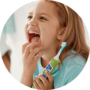 Dziecko trzyma szczoteczkę soniczną z kolorowym uchwytem i białą główką. Dziecko jest uśmiechnięte i ma otwarte usta.