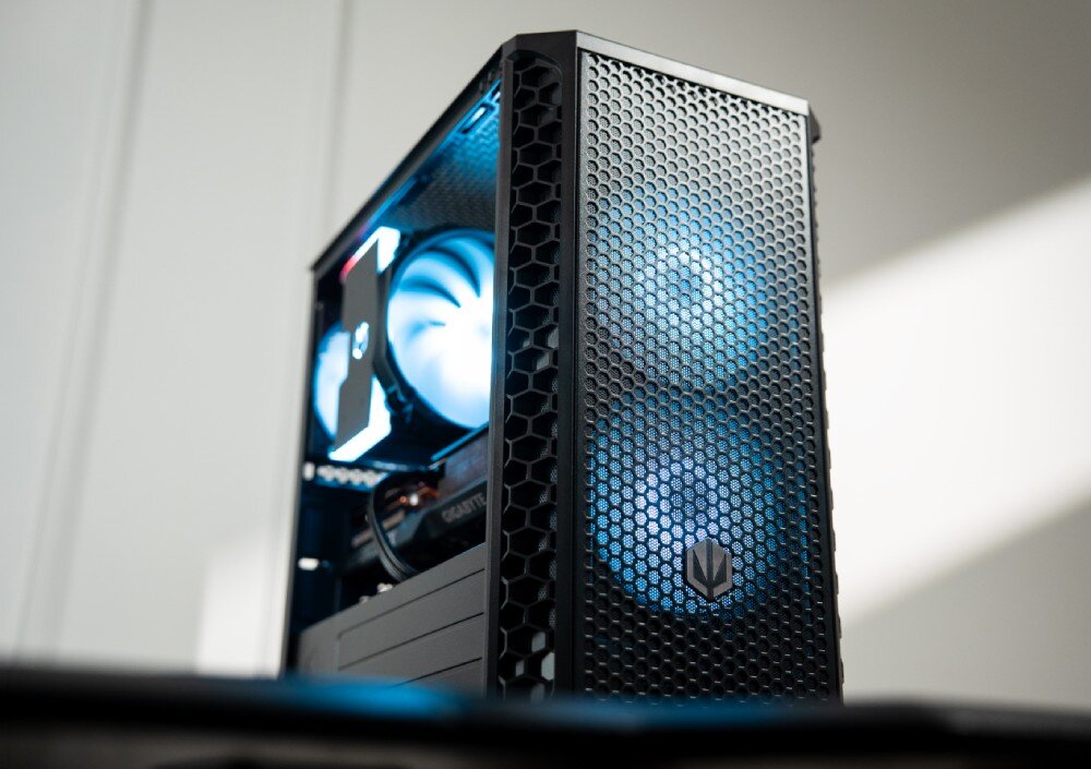 Obudowa komputerowa z siatkowym frontem, przez który widać podświetlone wentylatory. Wewnątrz obudowy znajdują się komponenty komputerowe z widocznym logo producenta.