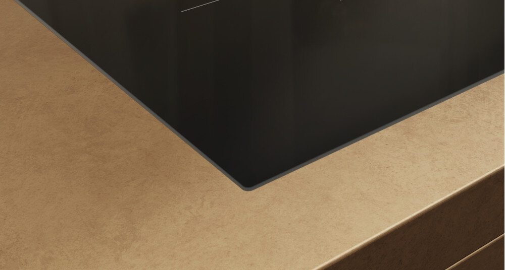 PŁYTA MIELE KM 8462 FL SERIA KM8000 Detal krawędzi płyty indukcyjnej osadzonej w jasnym blacie – widoczne cienkie, eleganckie wykończenie szkła szkło-ceramika minimalistyczny design montaż zlicowany elegancja
