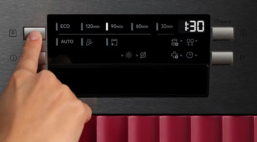 Palec naciskający przycisk na panelu sterującym zmywarki