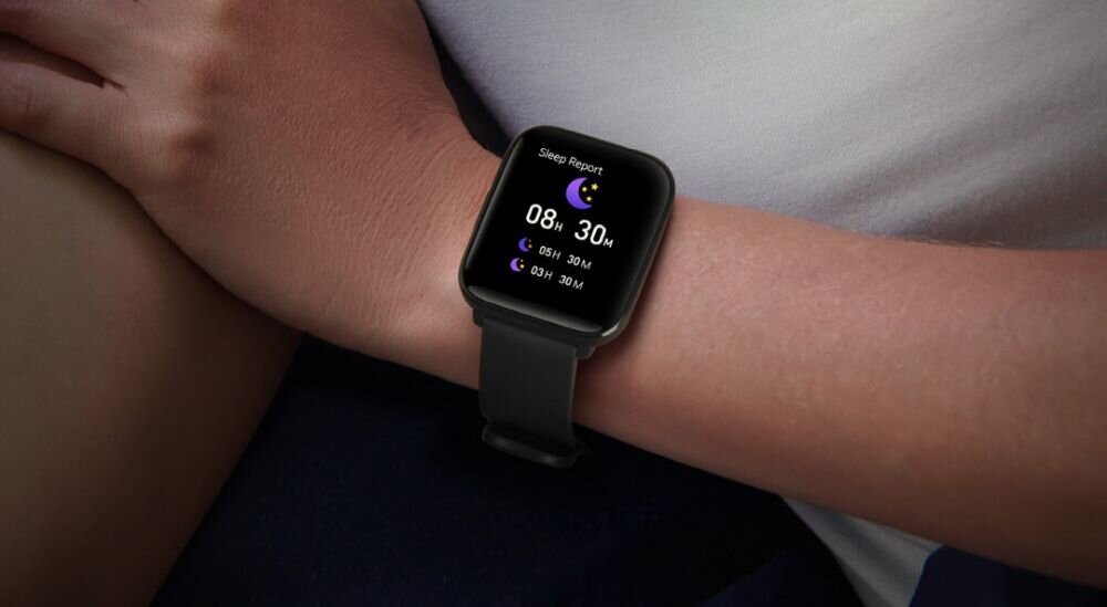 Na nadgarstku osoby znajduje się smartwatch z czarnym paskiem. Na ekranie widoczny jest raport snu z ikoną księżyca i czasem 08h 30m.