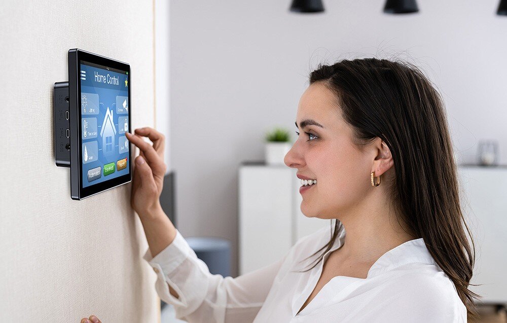 Monitor UPERFECT UPI B7 Kobieta dotykająca ekranu zamontowanego na ścianie, na wyświetlaczu widoczny interfejs do sterowania domem, sterowanie, ekran dotykowy