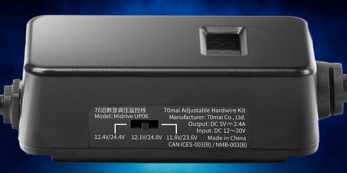 Czarny adapter samochodowy z widocznymi oznaczeniami technicznymi na obudowie. Tekst na urządzeniu: \'70mai Adjustable Hardwire Kit Model: Midrive UP06 Manufacturer: 70mai Co., Ltd. Output: DC 5V--2.4A Input: DC 12~30V Made in China CAN ICES-003(B)/NMB-003(B)\'.