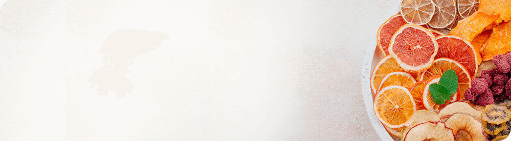 Na obrazie widoczny jest talerz z różnymi suszonymi owocami, takimi jak pomarańcze, cytryny, jabłka i maliny. Tło jest jasne i jednolite.