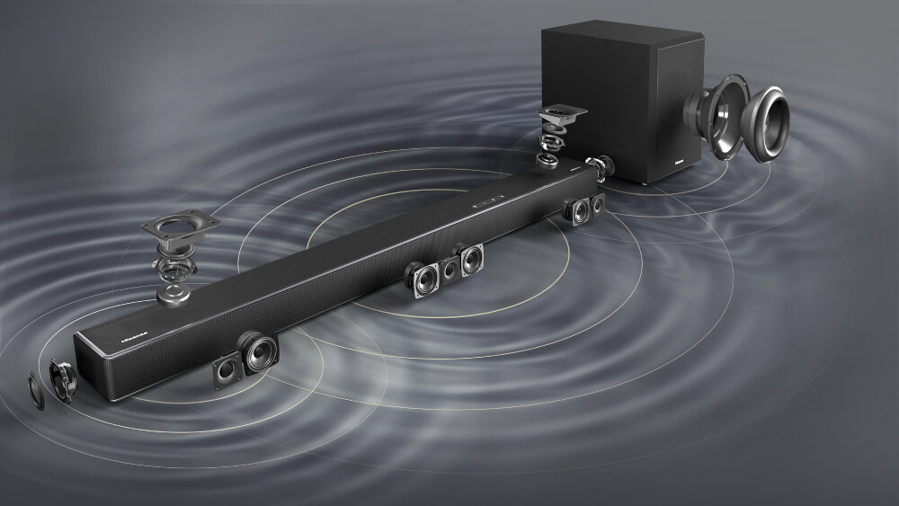 Na obrazie widoczny jest soundbar z kilkoma głośnikami oraz bezprzewodowy subwoofer, z efektami wizualnymi przedstawiającymi fale dźwiękowe. Logo producenta znajduje się na urządzeniach.