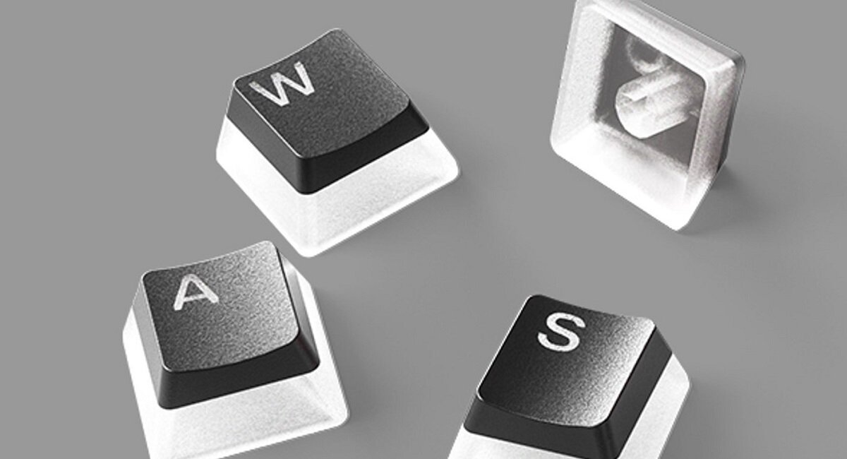 Na szarym tle widoczne są cztery czarne klawisze z białymi literami: W, A, S oraz jeden klawisz odwrócony, ukazujący przezroczystą podstawę.