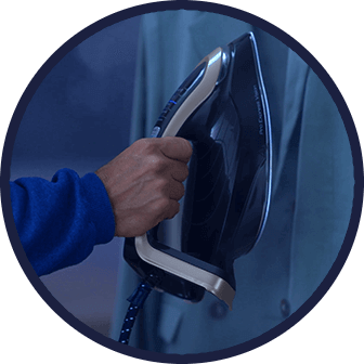 Osoba trzyma żelazko z ciemną obudową i jasnym uchwytem, prasując ubranie. Na żelazku widoczny jest napis \'Pro Express Vision\'.