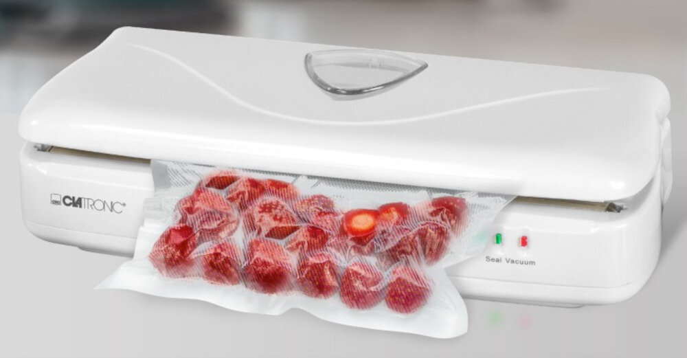Biała zgrzewarka z logo \'CLATRONIC\' na obudowie, z której wystaje worek z zgrzanymi truskawkami. Obok znajdują się dwa wskaźniki świetlne i napis \'Seal Vacuum\'.