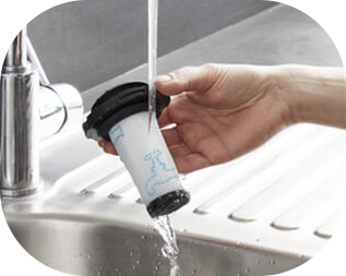 Osoba trzyma filtr odkurzacza pod strumieniem wody z kranu nad zlewem.