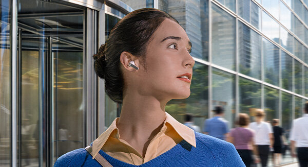 Kobieta z białą słuchawką Galaxy Buds4 Pro w uchu, spogląda w prawo.