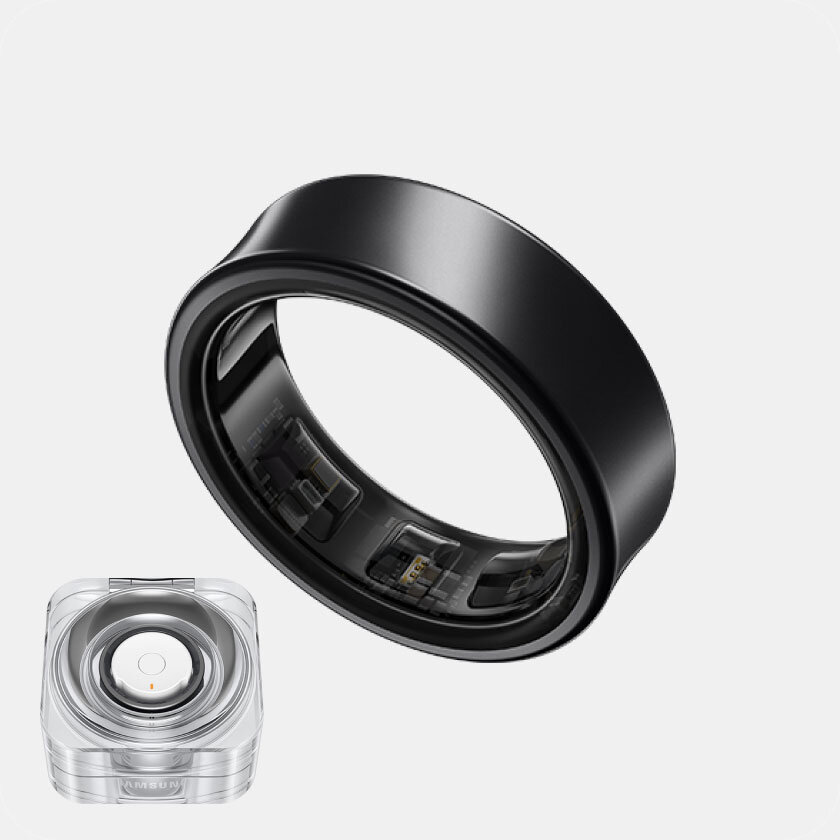 Obraz przedstawia czarny pierścień z widocznymi elementami elektronicznymi wewnątrz. Obok znajduje się przezroczyste opakowanie z okrągłym elementem w środku, na którym widnieje napis \'SAMSUNG\'.