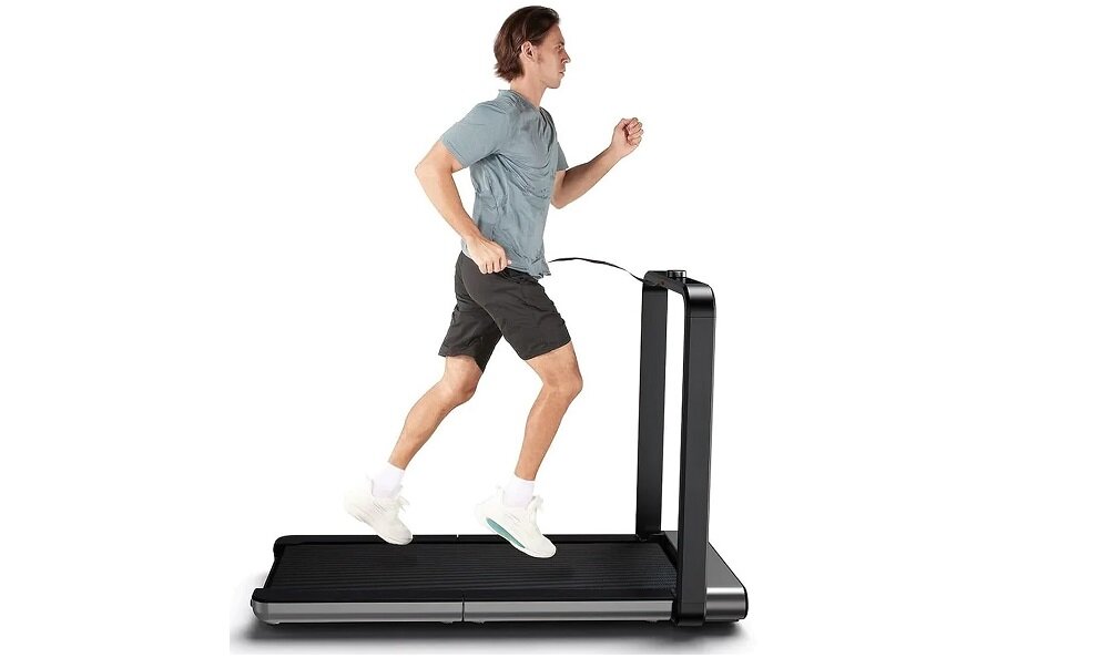 Osoba biegnie na czarnej bieżni elektrycznej z pionowym uchwytem. Bieżnia ma prosty, nowoczesny design.
