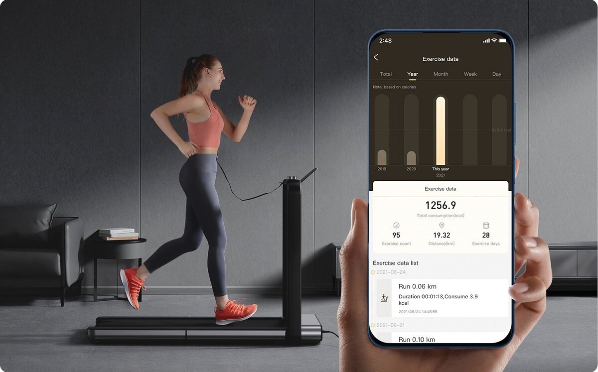 Osoba biegnie na bieżni elektrycznej w nowoczesnym wnętrzu, obok widoczny jest ekran smartfona z aplikacją pokazującą dane z ćwiczeń. Na ekranie widnieje tekst: \'Exercise data\', \'1256.9\', \'Total consumption(kcal)\'.