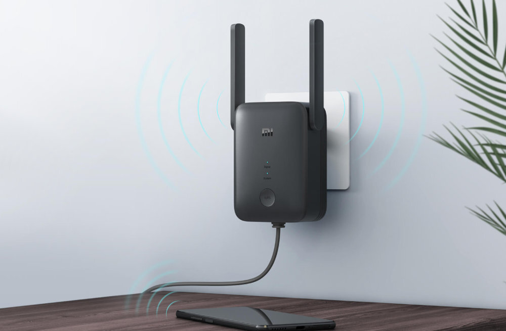 Czarny wzmacniacz sieciowy z dwoma antenami podłączony do gniazdka ściennego, z widocznymi niebieskimi falami sygnalizującymi działanie. Na urządzeniu znajduje się logo \'mi\' oraz trzy diody sygnalizacyjne.