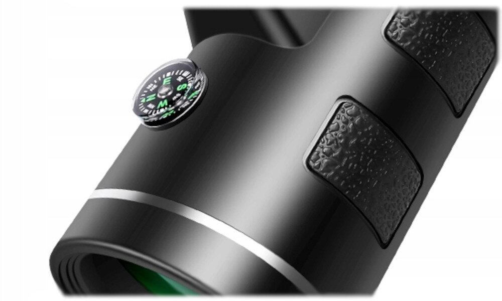 Obraz przedstawia czarny monokular z widocznym kompasem na górze. Monokular ma teksturowane uchwyty i zielone szkło obiektywu.