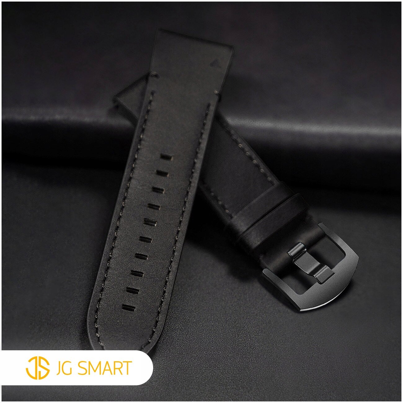 Czarny skórzany pasek do zegarka z metalową klamrą, widoczny na ciemnym tle. W lewym dolnym rogu znajduje się logo \'JG SMART\'.
