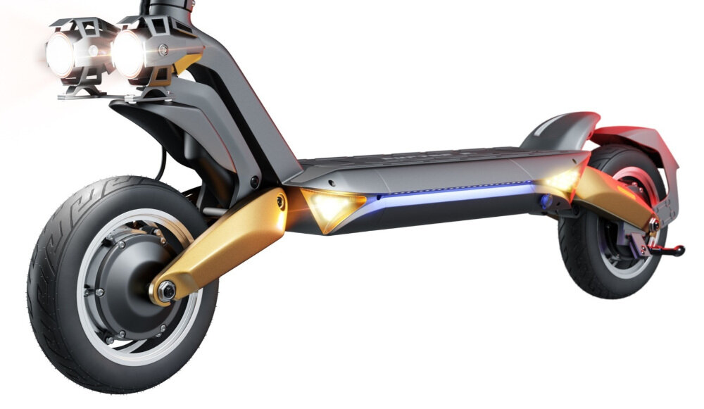 Na obrazie widoczna jest elektryczna hulajnoga z dużymi kołami i podwójnymi reflektorami z przodu. Posiada miedziane elementy konstrukcyjne oraz oświetlenie LED wzdłuż podestu.