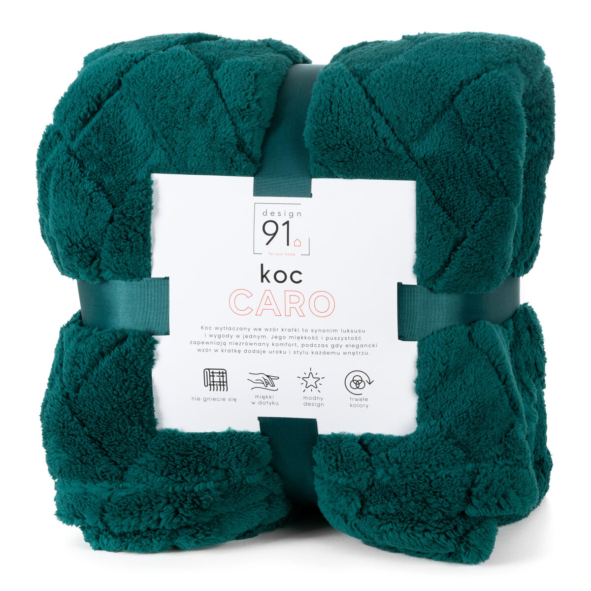 Pluszowy koc w kolorze ciemnej zieleni z wzorem jodełki, zapakowany z etykietą z napisem \'design 91 koc CARO\'. Etykieta zawiera informacje o właściwościach koca, takich jak miękkość, modny design i trwałe kolory.