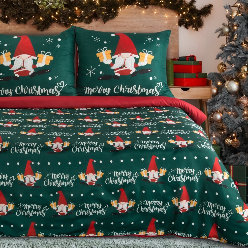 Zielona pościel z motywem świątecznym przedstawiającym krasnale trzymające prezenty oraz napis \'Merry Christmas\'. W tle widoczne są świąteczne dekoracje i choinka.