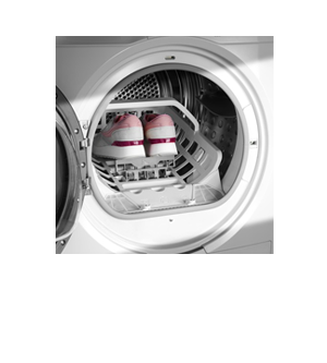 Otwarta suszarka bębnowa z widocznymi butami sportowymi umieszczonymi na specjalnej półce wewnątrz bębna. Wnętrze suszarki jest metaliczne, a obudowa zewnętrzna biała.